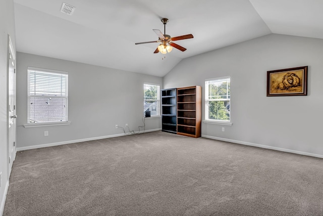 carpeted spare room featuring ceiling fan, lofted ceiling, and a wealth of natural light