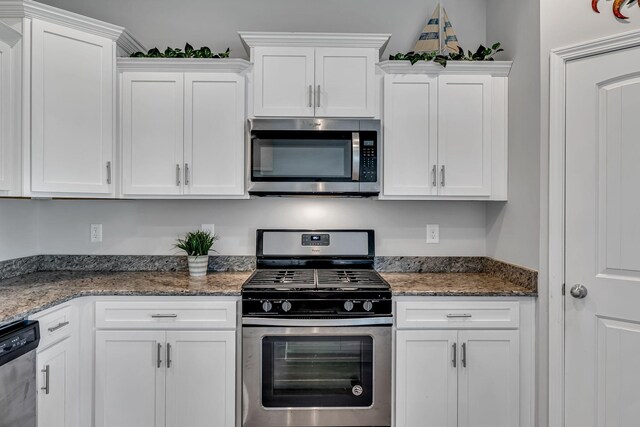 kitchen with stainless steel appliances, white cabinetry, and dark stone counters