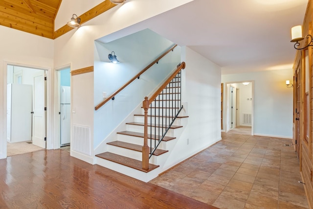 staircase featuring high vaulted ceiling and wood-type flooring