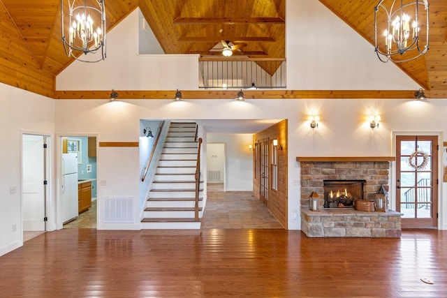 unfurnished living room featuring a fireplace, high vaulted ceiling, ceiling fan with notable chandelier, and hardwood / wood-style flooring