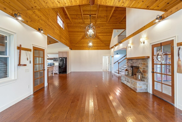 unfurnished living room with french doors, wooden ceiling, a brick fireplace, high vaulted ceiling, and wood-type flooring