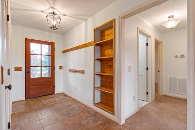 entryway with light carpet and a chandelier