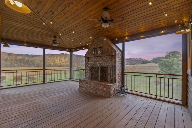 deck at dusk featuring an outdoor brick fireplace and ceiling fan