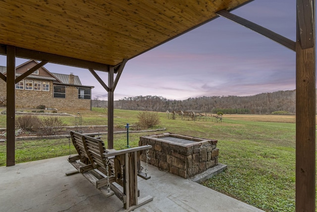 patio terrace at dusk with a lawn and an outdoor fire pit