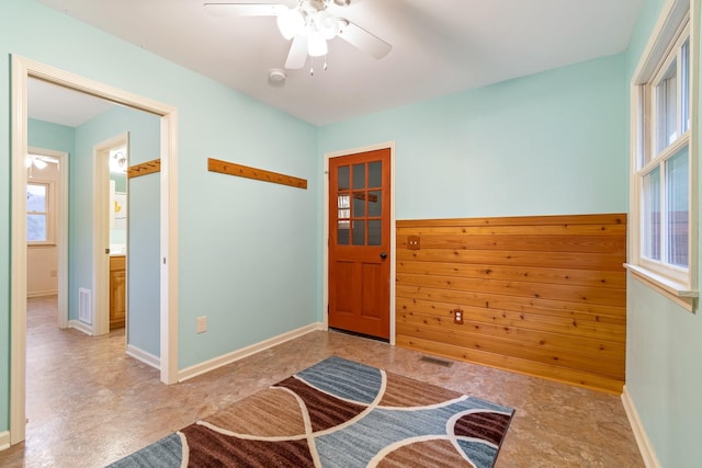 living area featuring ceiling fan and wood walls