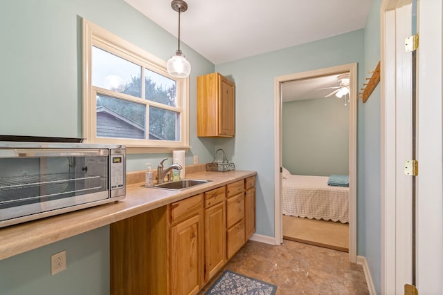 kitchen featuring ceiling fan, sink, and pendant lighting