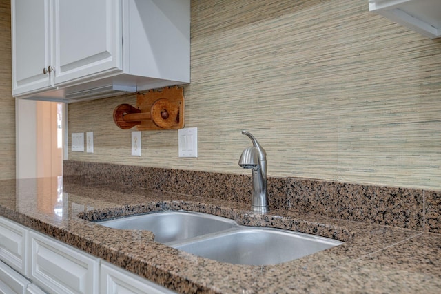 room details featuring white cabinets, dark stone countertops, and sink