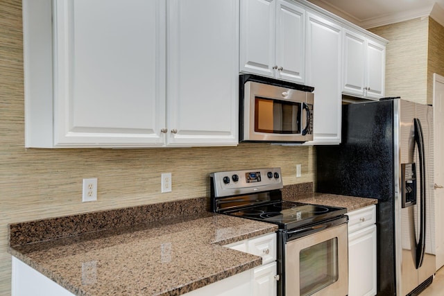 kitchen featuring ornamental molding, stainless steel appliances, white cabinetry, and dark stone counters