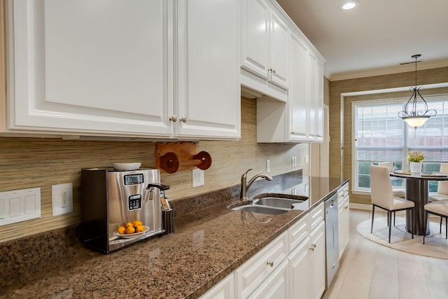 kitchen with dishwasher, white cabinets, sink, dark stone countertops, and decorative light fixtures