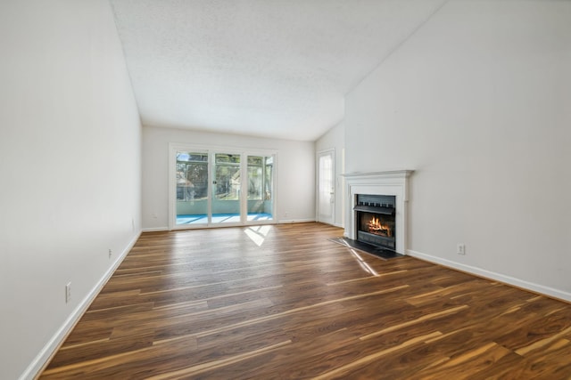 unfurnished living room featuring a textured ceiling, dark hardwood / wood-style flooring, and lofted ceiling