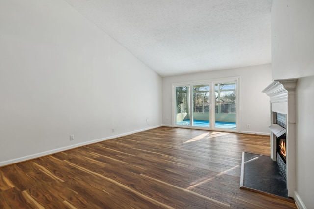 unfurnished living room featuring lofted ceiling, dark hardwood / wood-style floors, and a textured ceiling