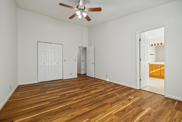 unfurnished bedroom with a closet, ensuite bath, dark hardwood / wood-style floors, and ceiling fan