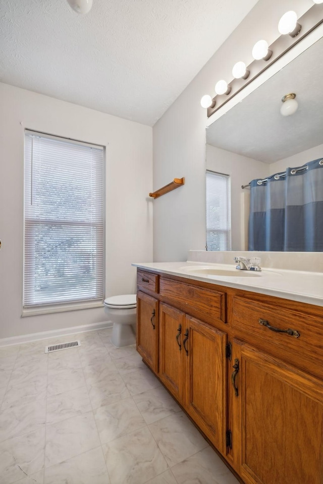 bathroom with vanity, toilet, a shower with shower curtain, and a textured ceiling