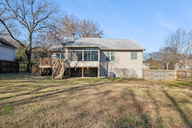 back of property with a wooden deck, a yard, and a sunroom