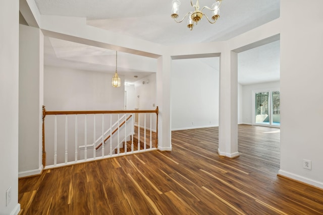 spare room featuring a notable chandelier and dark hardwood / wood-style flooring