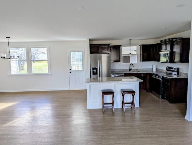 kitchen featuring sink, a center island, a notable chandelier, decorative light fixtures, and appliances with stainless steel finishes