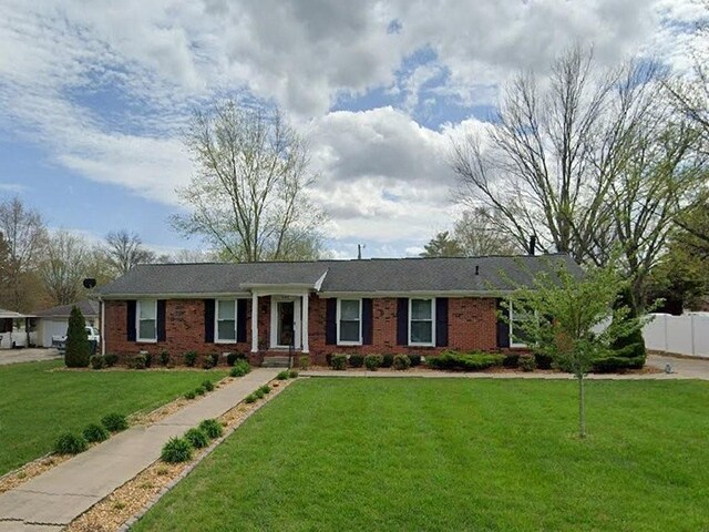 ranch-style home with a front yard, fence, and brick siding