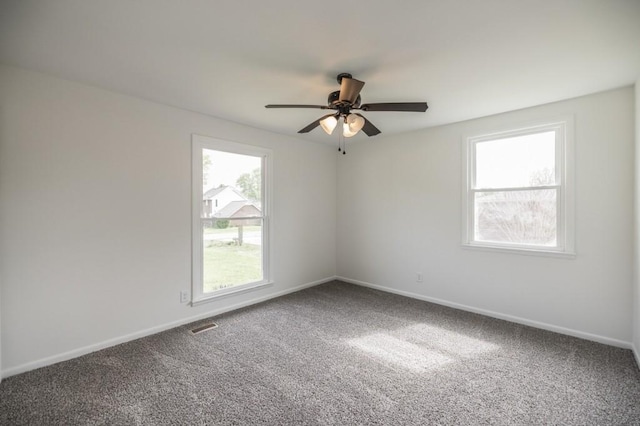 carpeted empty room with visible vents, baseboards, and a ceiling fan