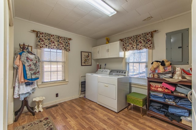 washroom with electric panel, a healthy amount of sunlight, cabinets, and washing machine and dryer