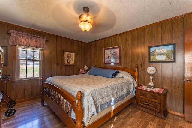 bedroom featuring wood walls, crown molding, ceiling fan, a textured ceiling, and dark hardwood / wood-style flooring