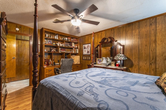 bedroom with ceiling fan, wooden walls, a textured ceiling, and light wood-type flooring