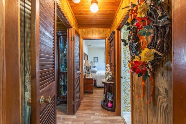 hall with hardwood / wood-style flooring, wood ceiling, and wooden walls