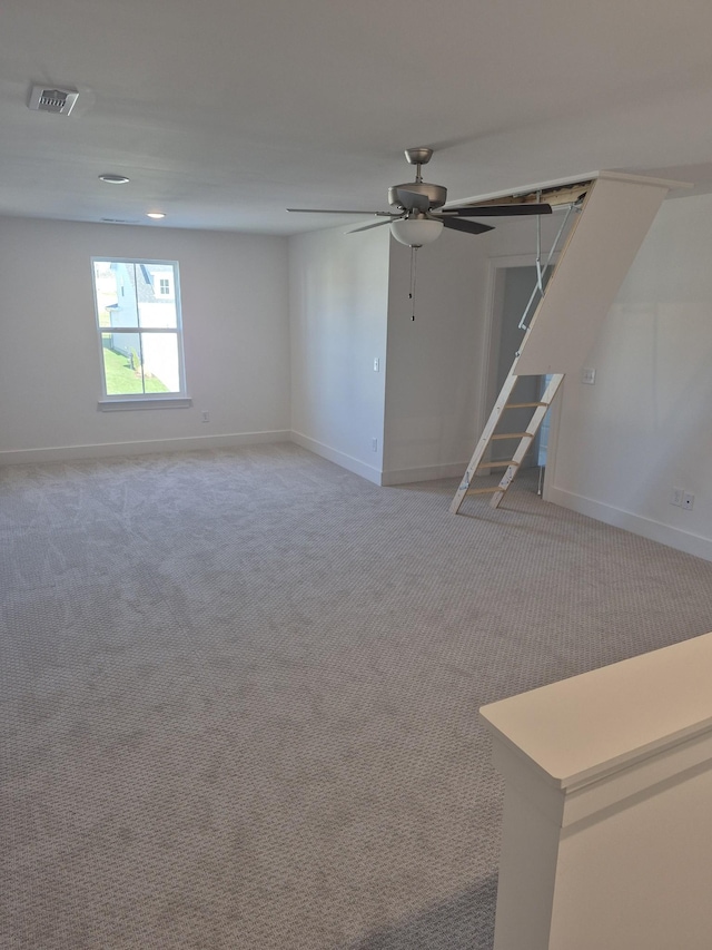 interior space featuring baseboards, ceiling fan, visible vents, and light colored carpet