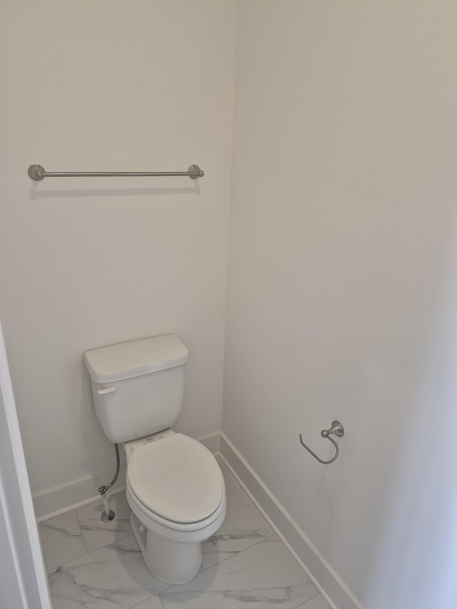 bathroom featuring toilet, marble finish floor, and baseboards