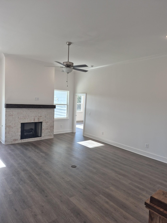 unfurnished living room with a fireplace, dark wood finished floors, baseboards, and ceiling fan