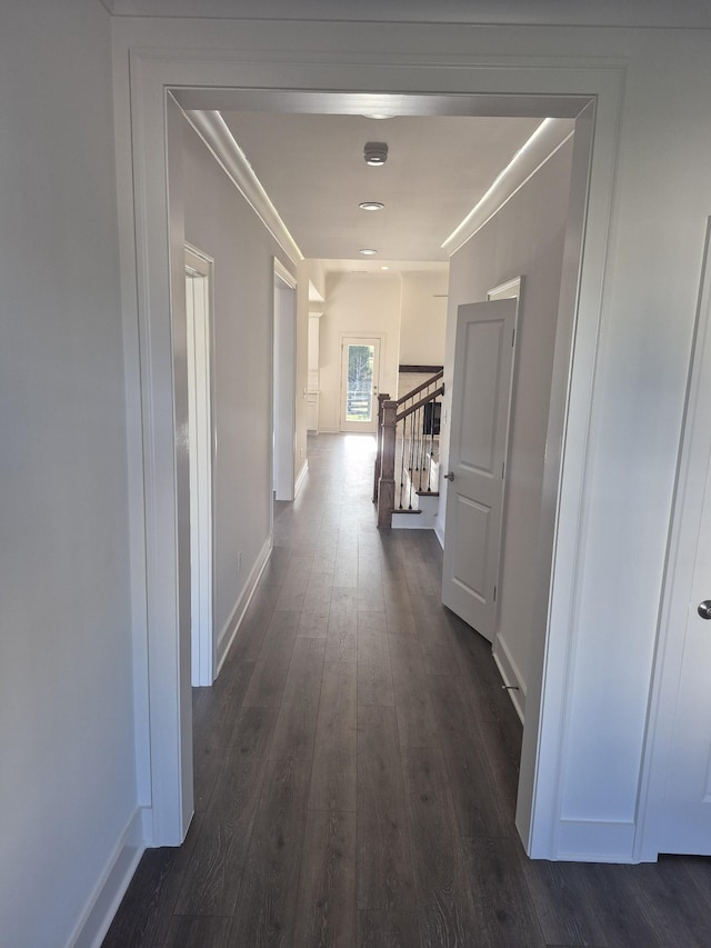 corridor with dark wood finished floors, baseboards, and stairs