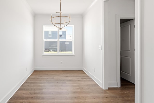 unfurnished dining area featuring visible vents, a notable chandelier, baseboards, and wood finished floors