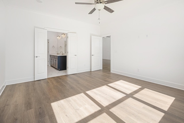 unfurnished bedroom featuring light wood-style flooring, ensuite bathroom, a ceiling fan, a sink, and baseboards