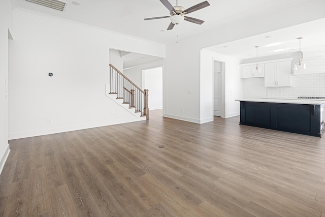 unfurnished living room featuring visible vents, stairway, a ceiling fan, wood finished floors, and baseboards