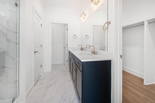 bathroom featuring double vanity, marble finish floor, ornamental molding, and a sink