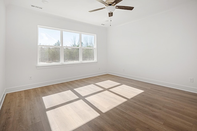 spare room with visible vents, wood finished floors, a ceiling fan, and baseboards