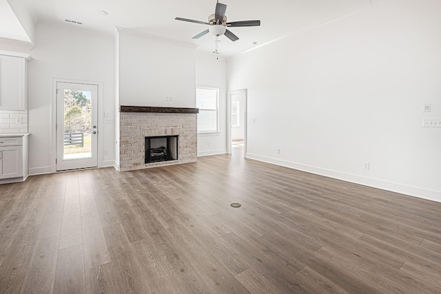 unfurnished living room featuring a fireplace, visible vents, wood finished floors, and ornamental molding