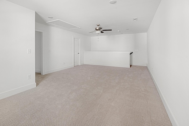 empty room featuring attic access, light carpet, and baseboards