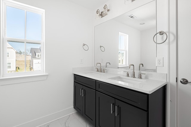 bathroom with double vanity, marble finish floor, baseboards, and a sink