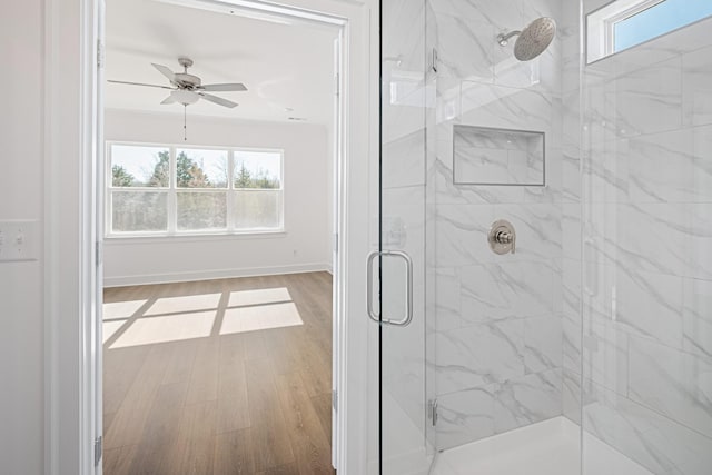 full bathroom featuring ceiling fan, wood finished floors, a marble finish shower, and a healthy amount of sunlight