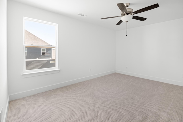 carpeted empty room featuring a ceiling fan, visible vents, and baseboards