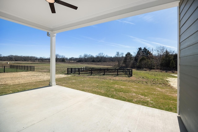 exterior space featuring a rural view, fence, a ceiling fan, and a patio