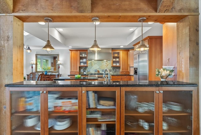 kitchen featuring built in refrigerator, pendant lighting, and wall chimney range hood