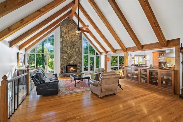 living room featuring hardwood / wood-style floors, beam ceiling, a fireplace, and high vaulted ceiling