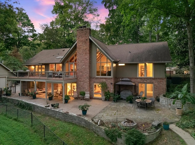 back house at dusk featuring a patio area and a balcony