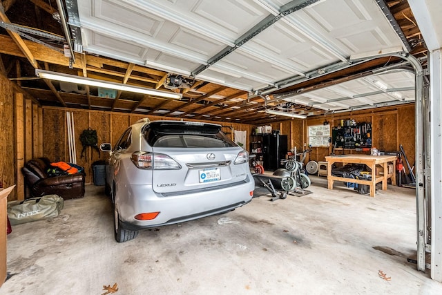 garage featuring a workshop area, wooden walls, and a garage door opener