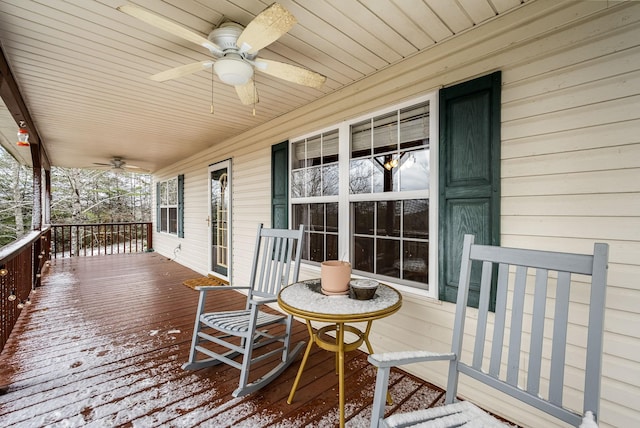 snow covered deck with ceiling fan and a porch