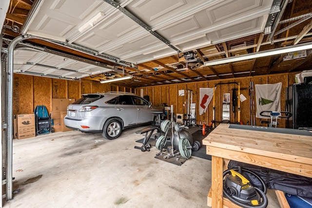 garage featuring wood walls, black fridge, and a garage door opener