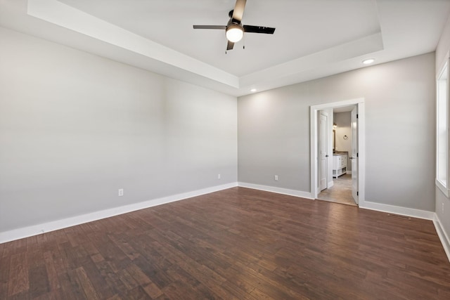 spare room featuring dark hardwood / wood-style floors, a raised ceiling, and ceiling fan