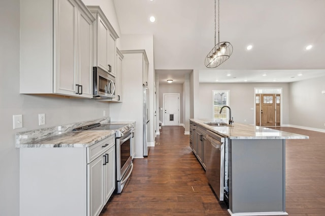 kitchen with light stone countertops, sink, hanging light fixtures, stainless steel appliances, and dark hardwood / wood-style flooring