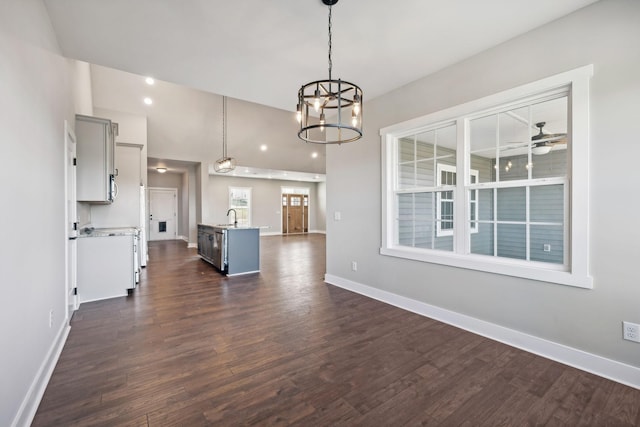 unfurnished living room with sink, dark wood-type flooring, and ceiling fan with notable chandelier